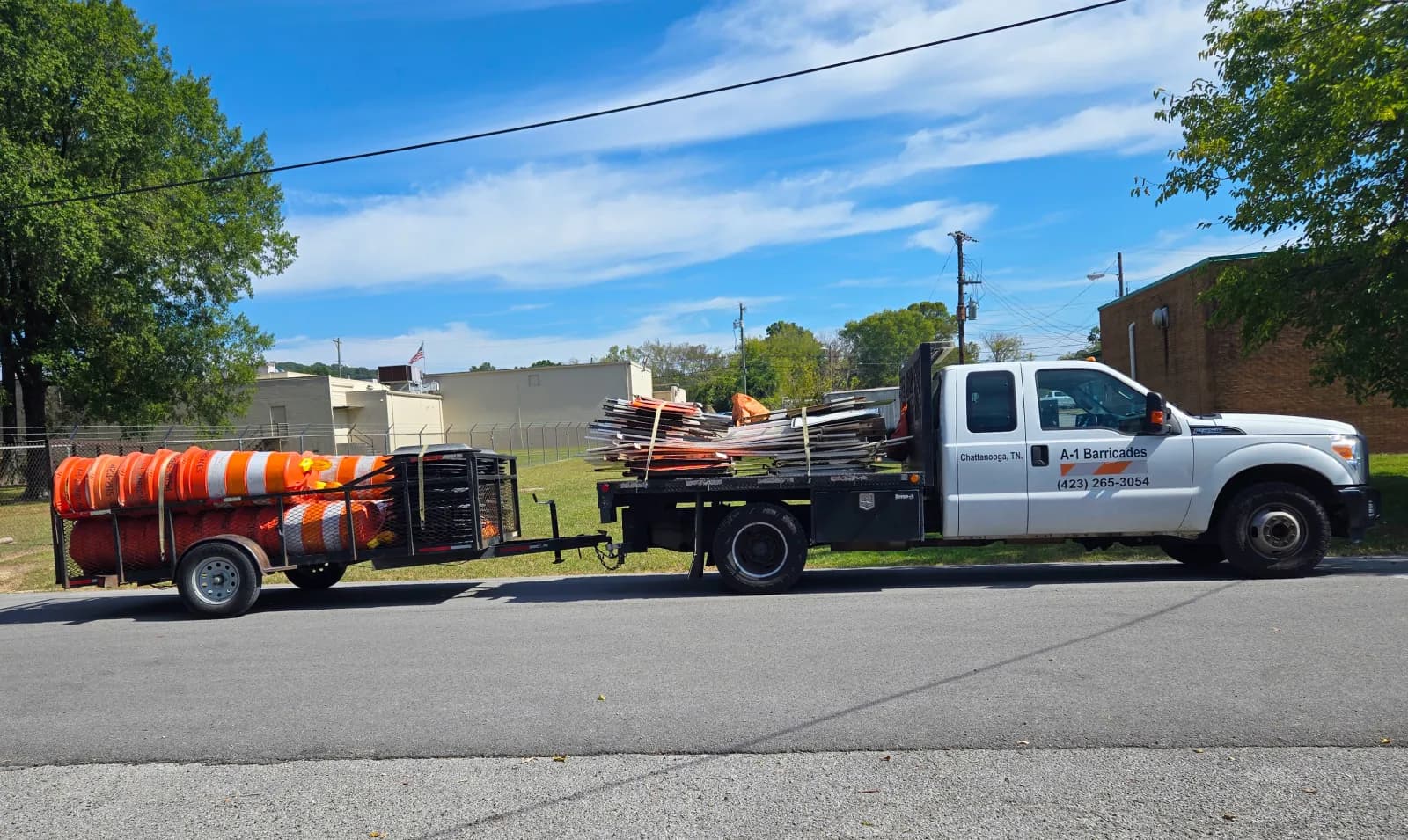 The A-1 Barricades flatbed truck loaded with barricades, towing a trailer of traffic drums