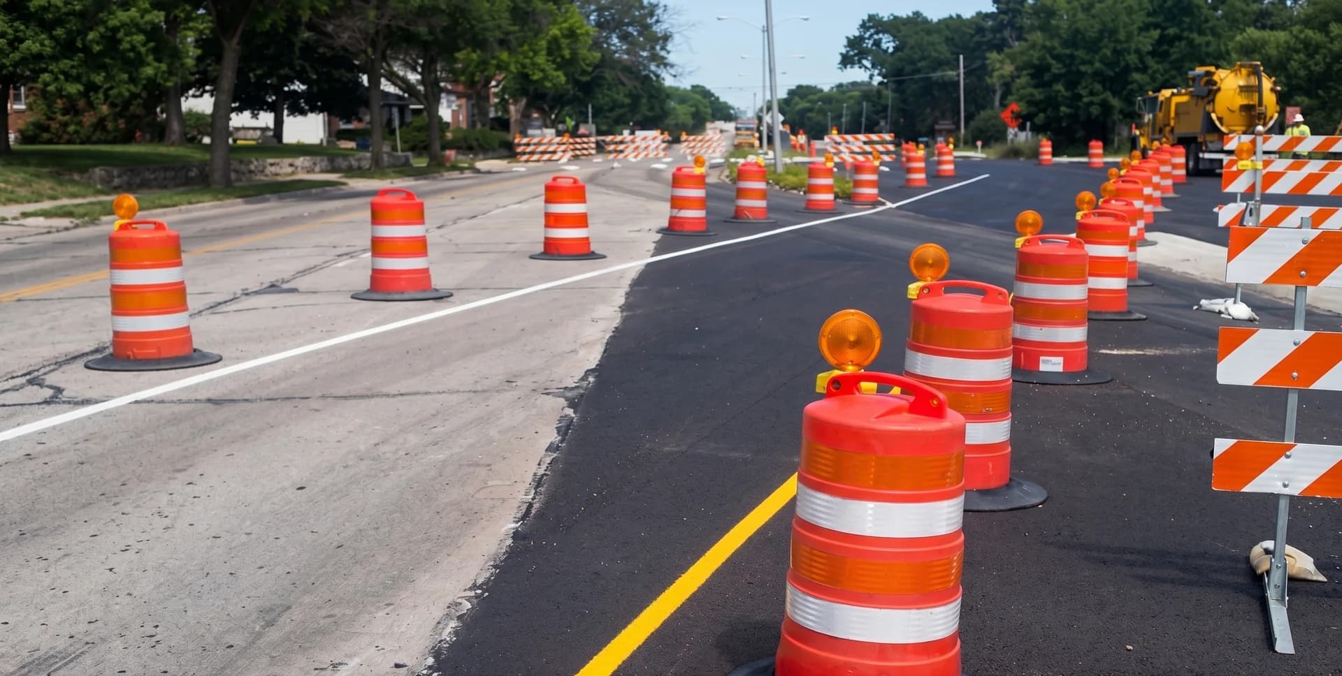 A line of orange traffic drums and cones channelizing a highway lane closure